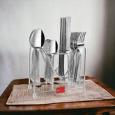 Complete stainless steel cutlery set in stand, placed on wooden table with woven beige mat.